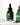 Eine dunkelgrüne Tropfflasche aus Glas mit der Aufschrift „Farm Loves Face AHA/BHA + Bio-Grünkohl Peeling Serum“ steht auf einer weißen Oberfläche und hebt die AHA- und BHA-Kraft dieses pflegenden Serums vor einem unscharfen Hintergrund mit einem weichen Schatten hervor.