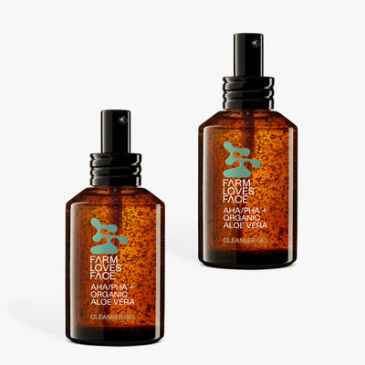 Zwei bernsteinfarbene Pumpflaschen mit der Aufschrift „Farm Loves Face AHA/PHA + Bio-Aloe Vera Reinigungsgel“ stehen aufrecht vor einem weißen Hintergrund.
