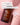 Eine braune Flasche mit der Aufschrift "Farm Loves Face Veganes Kollagen + Bio-Hafer Barriere & Hydro Toner + Gratis Socken" liegt auf pinkem Untergrund mit weißen Spritzern - ein Gesichtstoner zur Stärkung der Hautbarriere und intensiven Pflege.