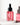 Eine rosa getönte Tropfflasche aus Glas mit der Aufschrift „Farm Loves Face Panthenol + Bio-Kastanie Calming Serum“ für empfindliche Haut steht auf einer weißen Oberfläche mit weichen Schatten im Hintergrund.