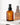 Eine braune Glasflasche Farm Loves Face Ceramide + Bio-Chicoree Barriere Hydro Creme mit einer schwarzen Pumpe steht auf einer weißen Oberfläche und wirft einen weichen Schatten und eine Reflexion – ideal zur Stärkung Ihrer Hautbarriere.