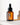 Eine braune Tropfflasche aus Glas mit der Aufschrift „Farm Loves Face Hyaluron + Bio-Feige 72h Hydro Serum“ steht auf einer weißen Oberfläche und spendet intensive Feuchtigkeit mit Hyaluronsäure, während im Hintergrund weiche Schatten fallen.